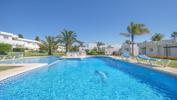 A swimming pool with a geometric tile pattern, surrounded by lounge chairs and palm trees. - 3 bedroom with private garden walking distance to everything (Marbella)