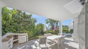 An outdoor patio with a grill, dining table, and chairs. - 3 bedroom with private garden walking distance to everything (Marbella)