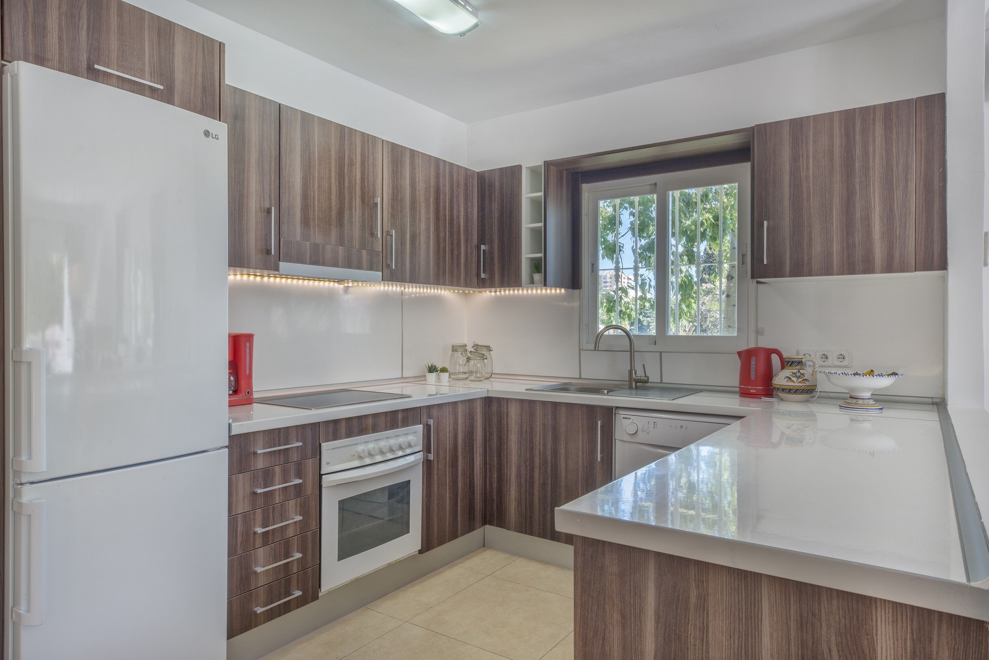 Eine moderne Küche mit Holzausstattung, einem weißen Kühlschrank, einem eingebauten Backofen und einer großen Kochinsel mit Spüle.