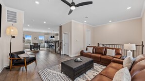 Ein geräumiges Wohnzimmer mit einem Couchtisch aus dunklem Holz, Ledersofas und einem Deckenventilator.