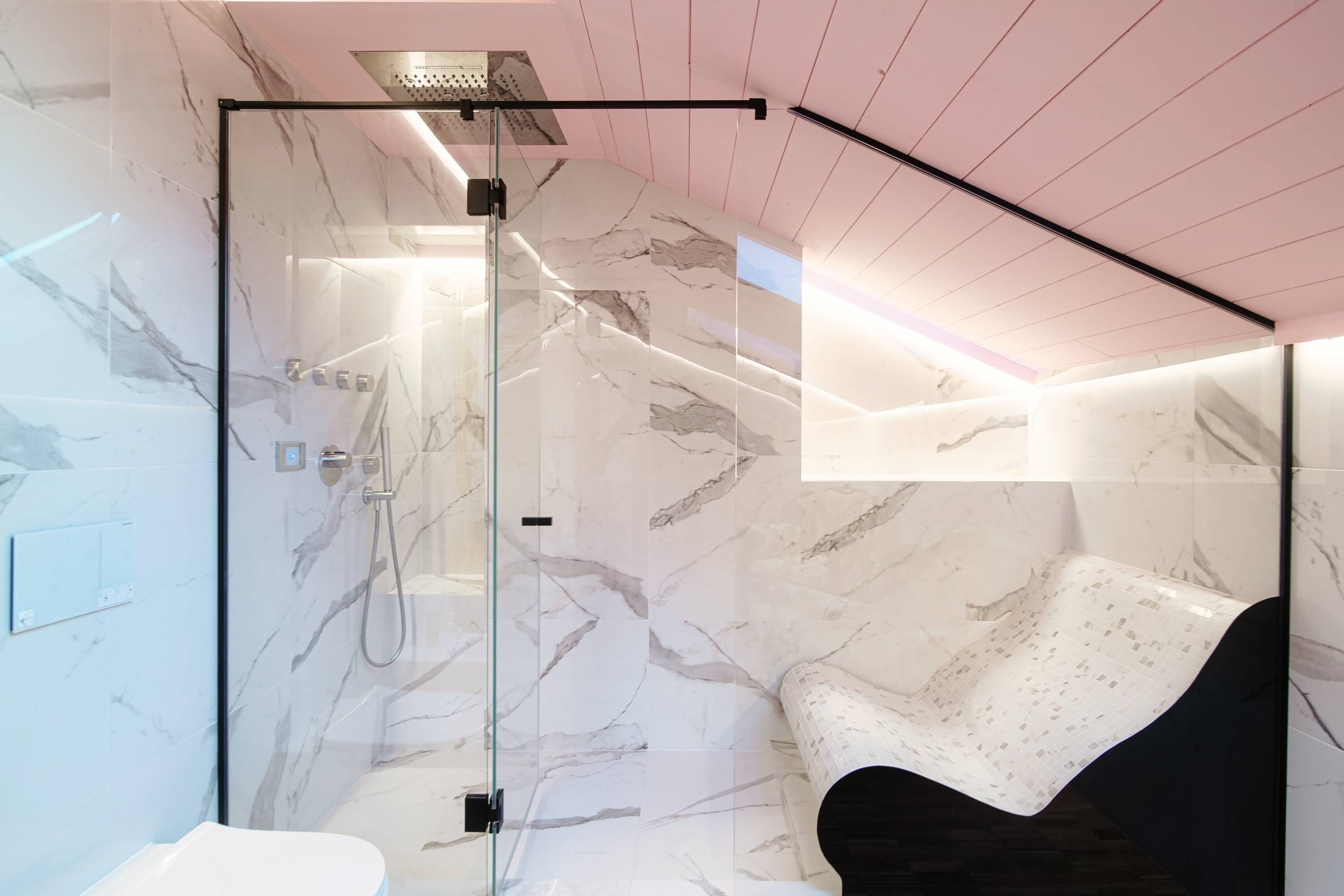 Ein modernes Badezimmer mit einer Duschkabine, Marmorwänden und einer schwarzen Badewanne.
