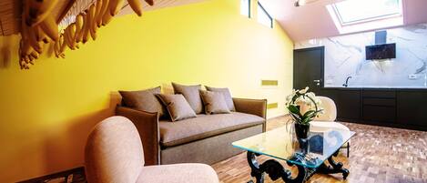 A modern living room with a yellow wall, a brown sofa, a glass coffee table, and a wooden floor.