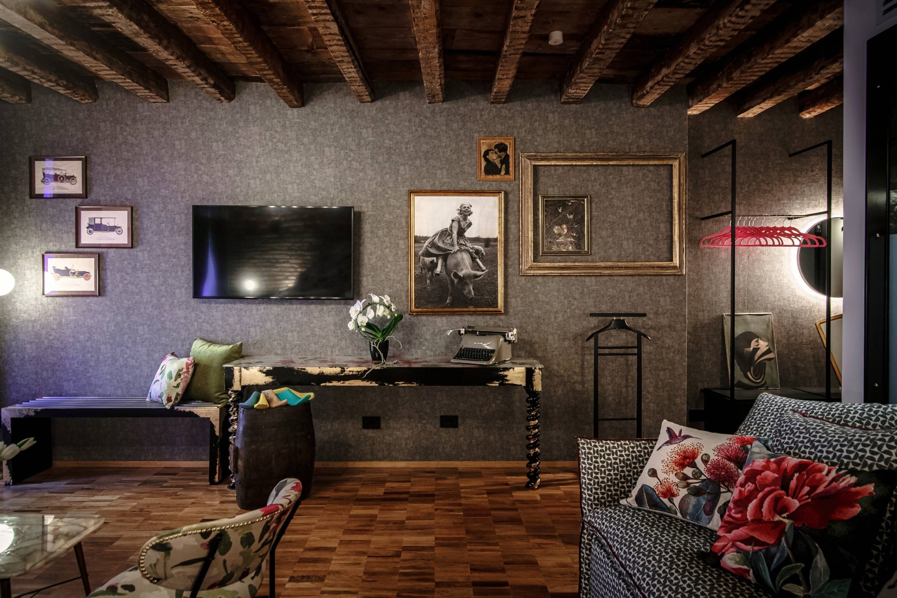 A cozy living room with a wooden ceiling, a flat-screen TV, a vintage typewriter, and a patterned sofa.