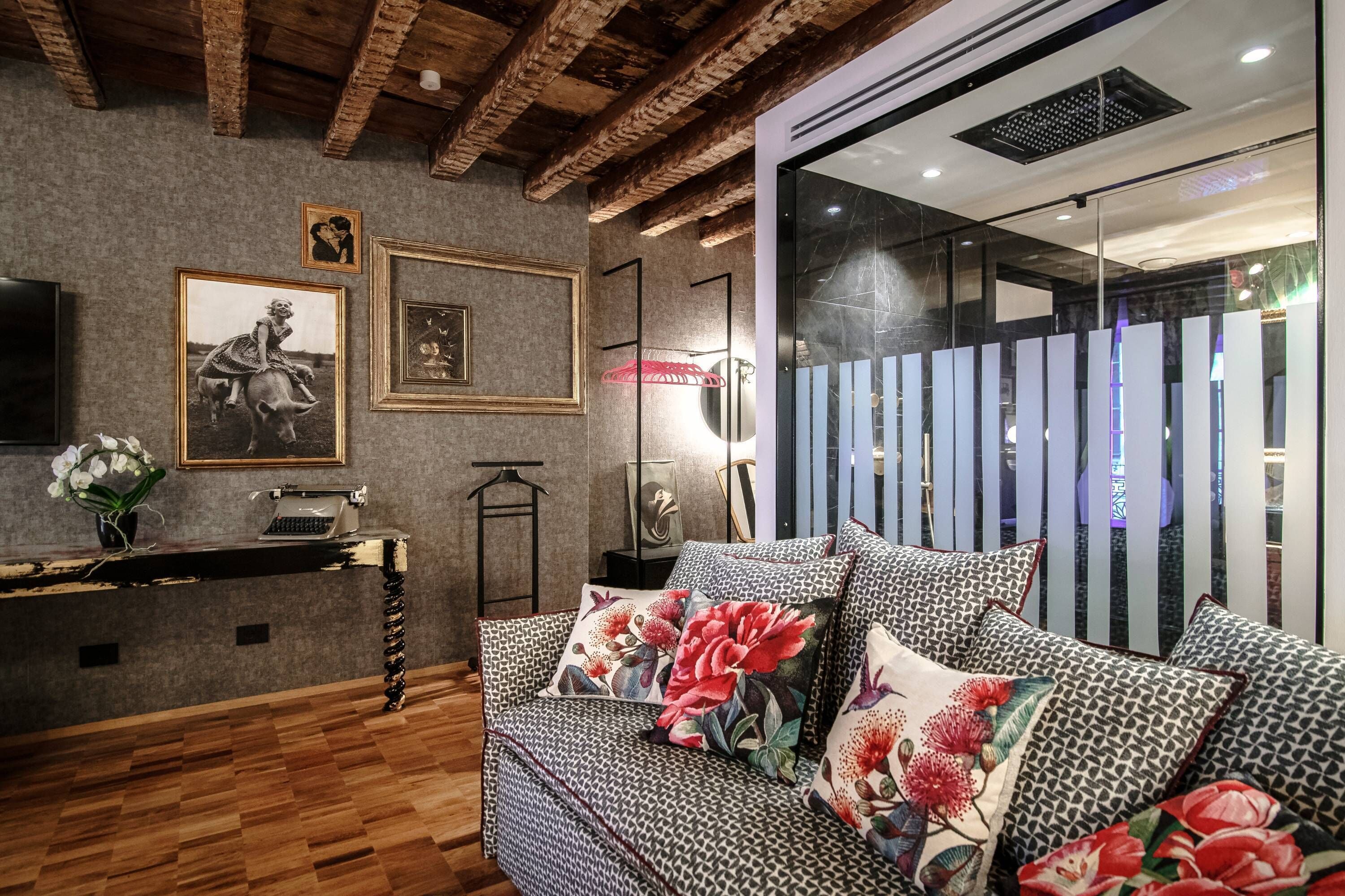 Una habitación acogedora con un sofá estampado, suelo de madera y una pared decorada con cuadros y una máquina de escribir.