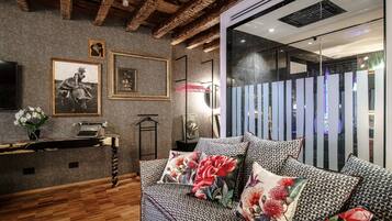 Una habitación acogedora con un sofá estampado, suelo de madera y una pared decorada con cuadros y una máquina de escribir.