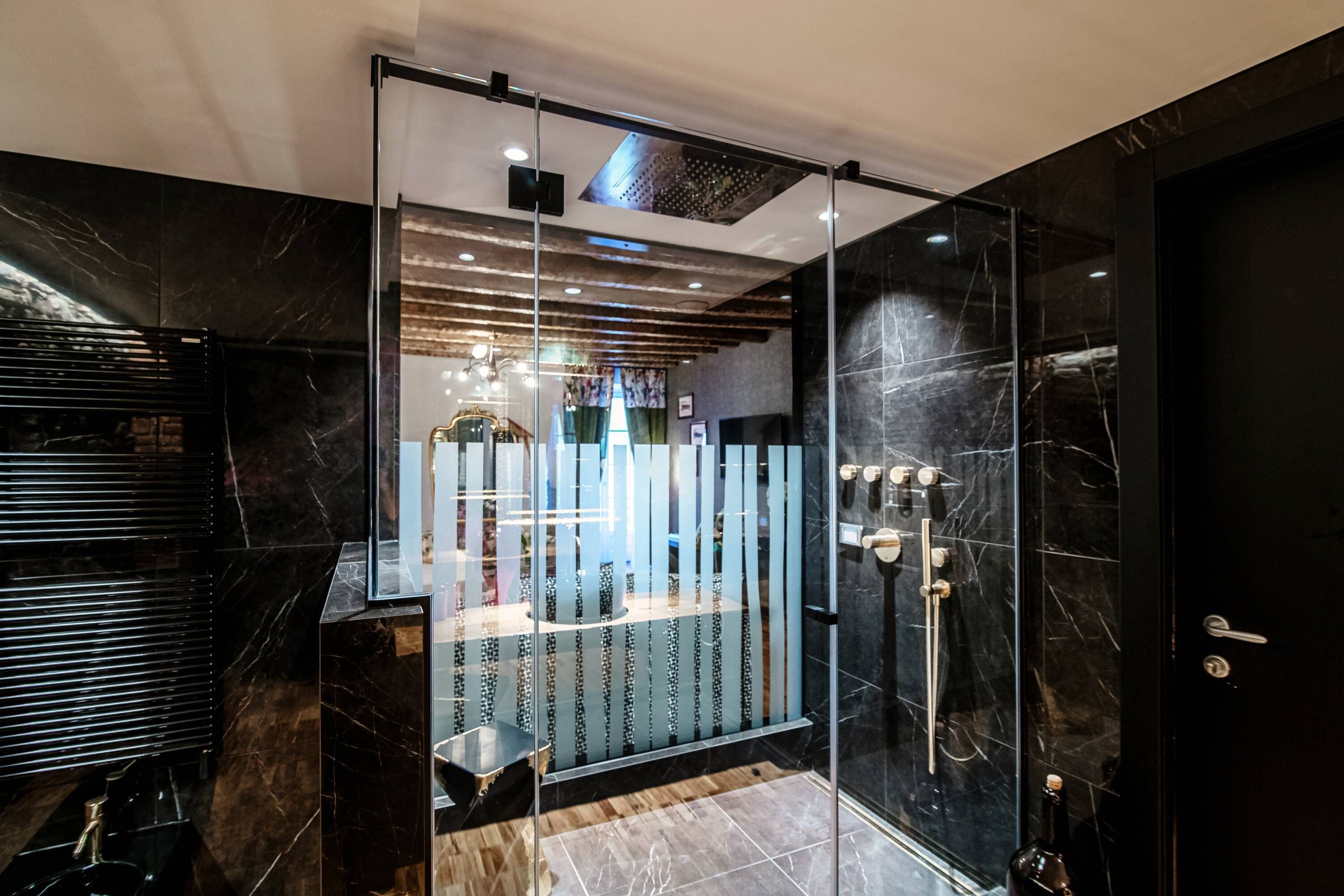 A modern bathroom with a glass shower enclosure, marble walls, and a wooden vanity.