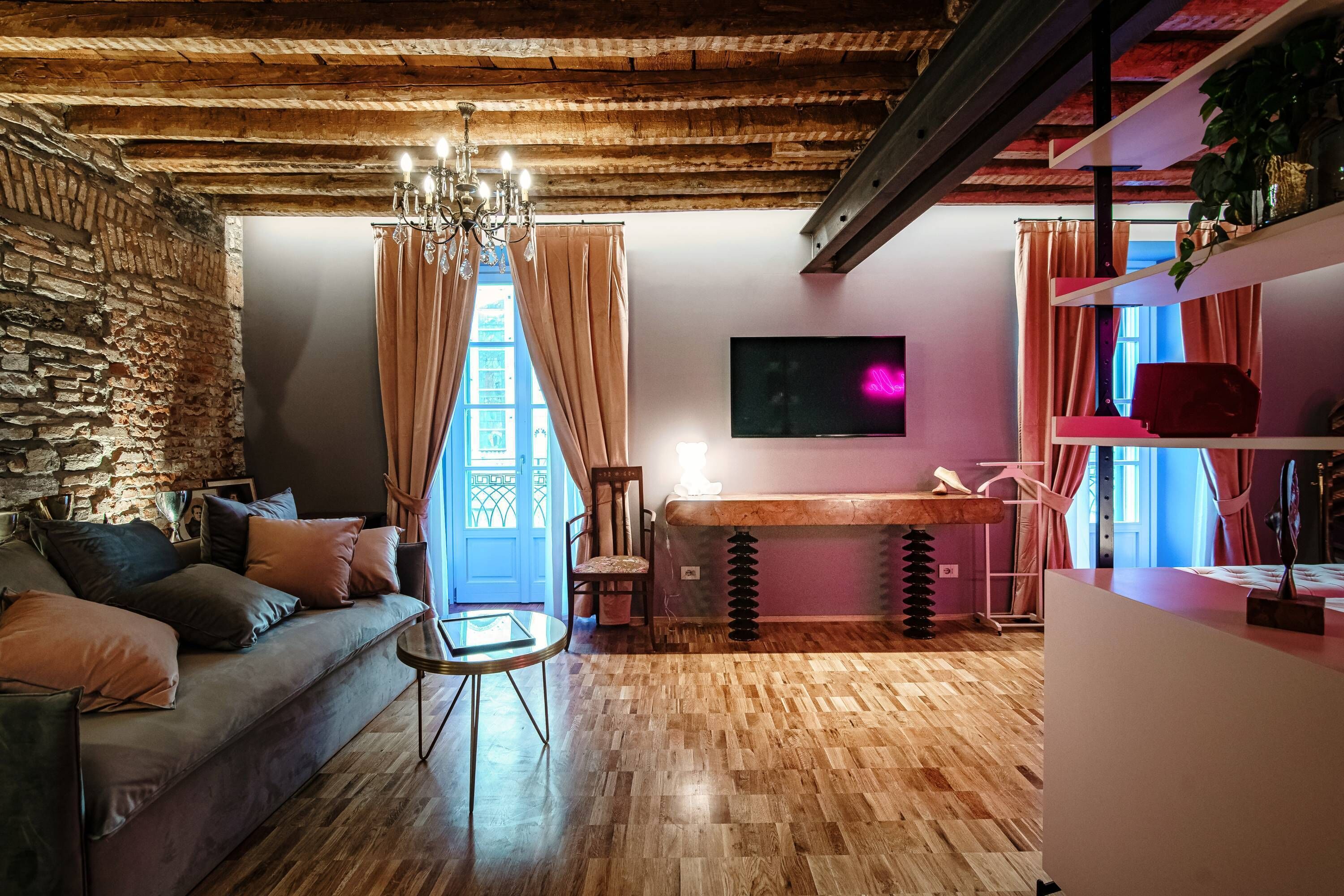 Una sala acogedora con pared de piedra, techo de madera y un gran ventanal con cortinas.