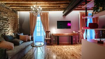 Una sala acogedora con pared de piedra, techo de madera y un gran ventanal con cortinas.