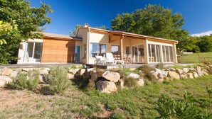A modern house with a patio area, large windows, and a stone foundation. - FranceComfort - L'Espinet (Quillan)