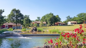 A tranquil outdoor setting with a pond, wooden fence, and red flowers. - FranceComfort - L'Espinet (Quillan)