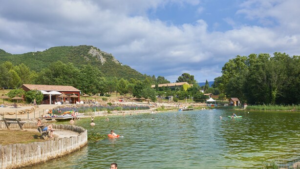 A lakeside scene with a wooden dock, boats, and people engaging in water activities. - FranceComfort - L'Espinet (Quillan)