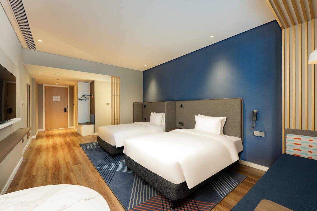 Ein Hotelzimmer mit zwei Betten, einem Schreibtisch und einem Fernseher.