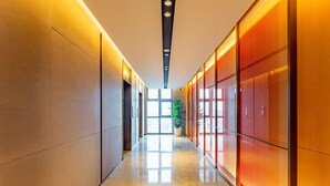 A modern hallway with a polished floor, recessed lighting, and a large window at the end. - Holiday Inn Express Haiyan by IHG (Jiaxing)