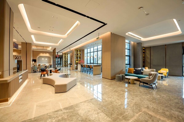 A modern hotel lobby with a reception desk, seating area, and large windows. - Holiday Inn Express Haiyan by IHG (Jiaxing)