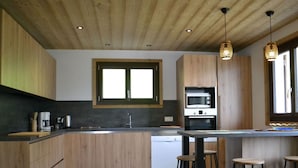 A modern kitchen with wooden cabinets, a built-in oven, and a large window. - Chalet 3 bedrooms, balcony, parking, pets allowed, 8 ppl. (Châtel)