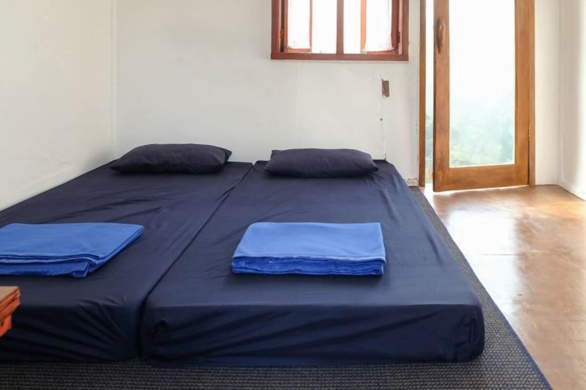 A room with two beds, a window, and a door leading outside.
