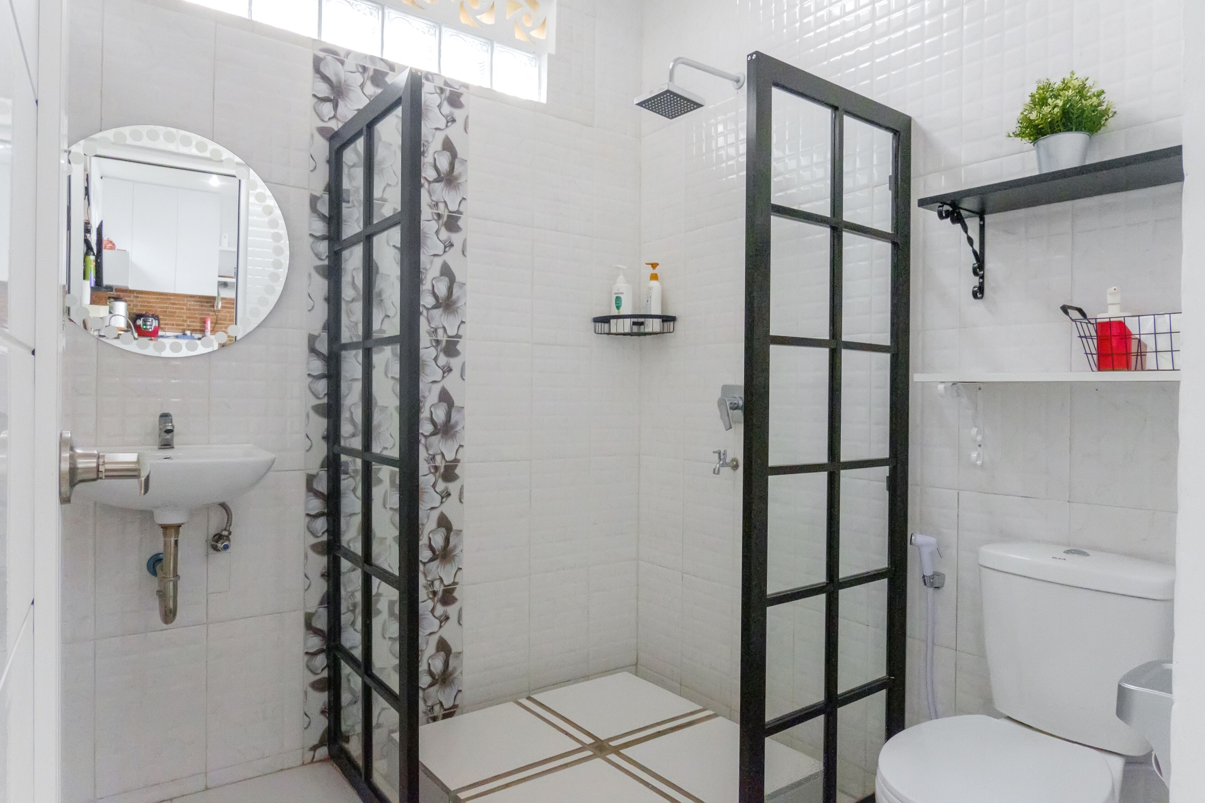 A bathroom with a toilet, sink, shower, and a glass door leading to a shower area.