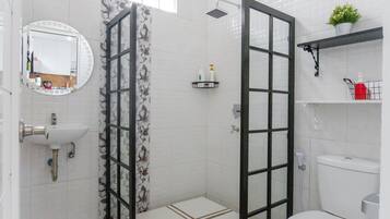 A bathroom with a toilet, sink, shower, and a glass door leading to a shower area.