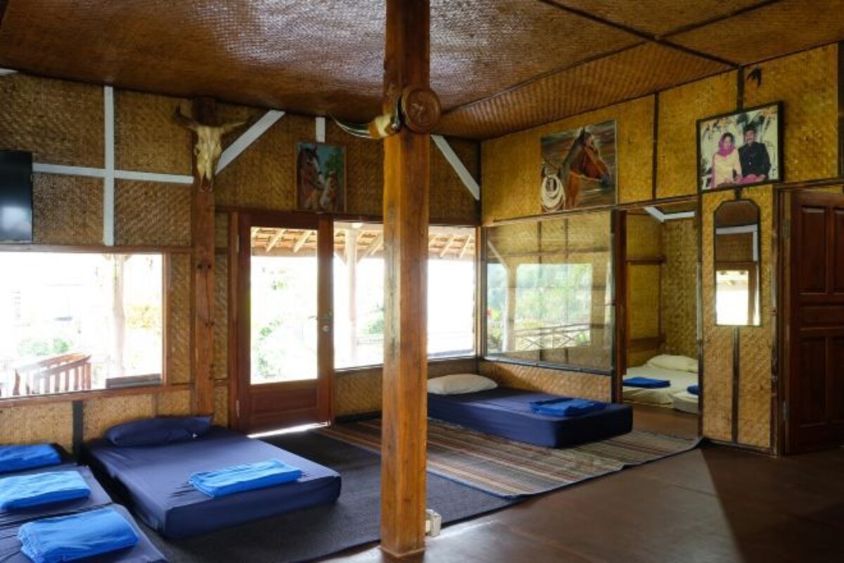 A room with wooden beams, a large mirror, and a bed with blue bedding.