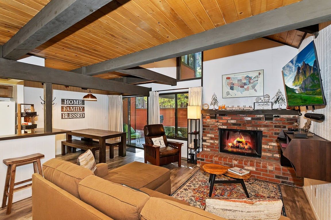 Una sala acogedora con chimenea, vigas de madera, un sofá y un comedor.