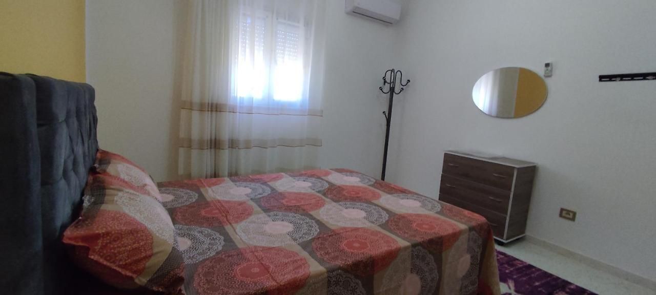 Ein Schlafzimmer mit Bett, Kommode, Heizkörper und einem Vorhangfenster.