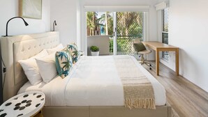 A bedroom with a bed, bedside table, and a desk with a chair. - Sunny Seaside Retreat in Coolum Beach (Coolum Region)