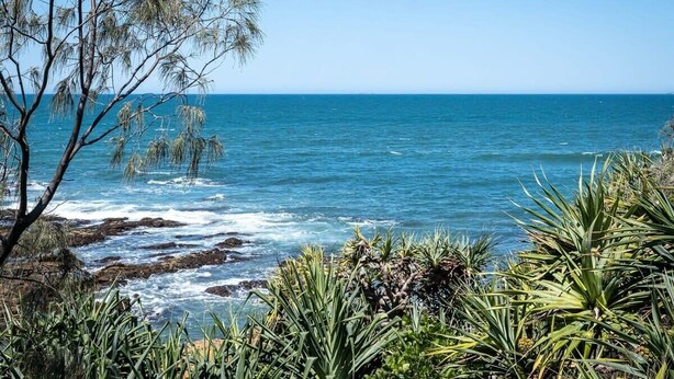 A coastal landscape with rocky terrain and vegetation. - Sunny Seaside Retreat in Coolum Beach (Coolum Region)