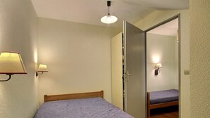 A bedroom with a bed, a wardrobe, and a mirror. - Spacious duplex for 5 at the foot of the slopes (Plagne Soleil)