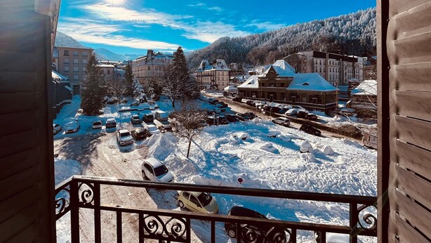A snowy town with buildings and parked cars.