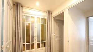 A hallway with a wooden floor, white doors, and grey curtains.