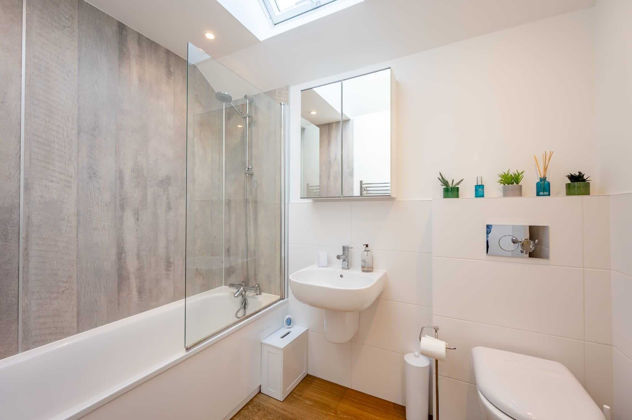 A modern bathroom with a glass-enclosed shower, a white sink, and a toilet.