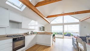Een moderne keuken met witte kasten, een inbouwoven en een groot raam met uitzicht op een balkon.