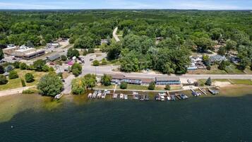 An aerial view of a lakeside property with a parking lot, buildings, and a road.