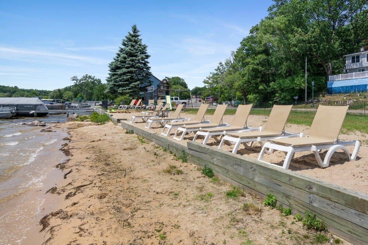 Una playa con tumbonas, una valla de madera y un árbol grande.