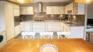A modern kitchen with white cabinets, a marble backsplash, a gas stove, and pendant lighting. - Spacious chalet for 8, close to center and lifts (Châtel)
