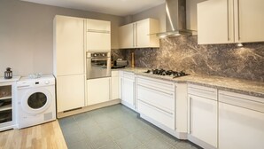 A modern kitchen with white cabinetry, a built-in oven, a gas stove, and a marble backsplash. - Spacious chalet for 8, close to center and lifts (Châtel)