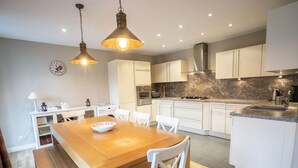 A modern kitchen with white cabinets, a wooden dining table, and pendant lighting. - Spacious chalet for 8, close to center and lifts (Châtel)