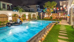 A swimming pool with a tiki float, surrounded by a well-lit garden with string lights and a wooden fence. - Lime Villa - King
Viziati in questa incantevole camera (Hội An)