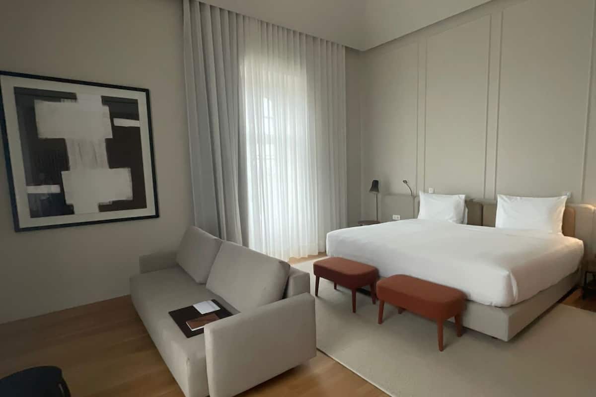 Una habitación de hotel moderna con una cama grande, un sofá, un escritorio y una silla.