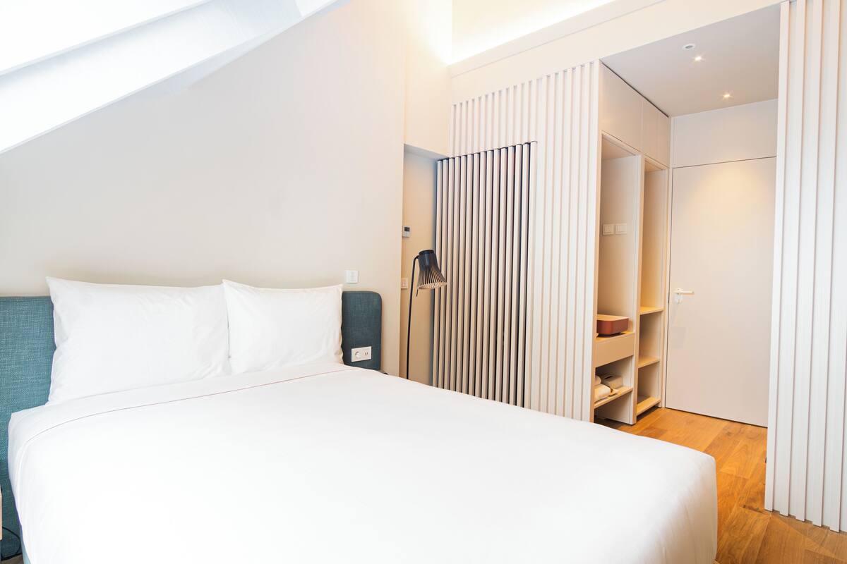 Una habitación de hotel moderna con una cama bien hecha, un armario y un vestidor.