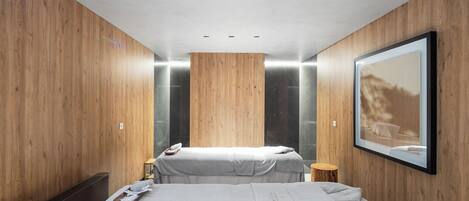 Una habitación de hotel moderna con paneles de madera, una cama grande con colcha blanca, una mesita de noche con lámpara y un cuadro enmarcado en la pared.