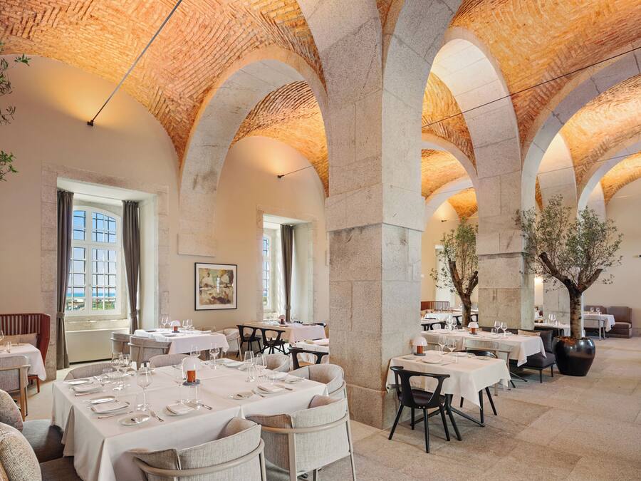 A spacious dining area with high arched ceilings and multiple tables set for dining.