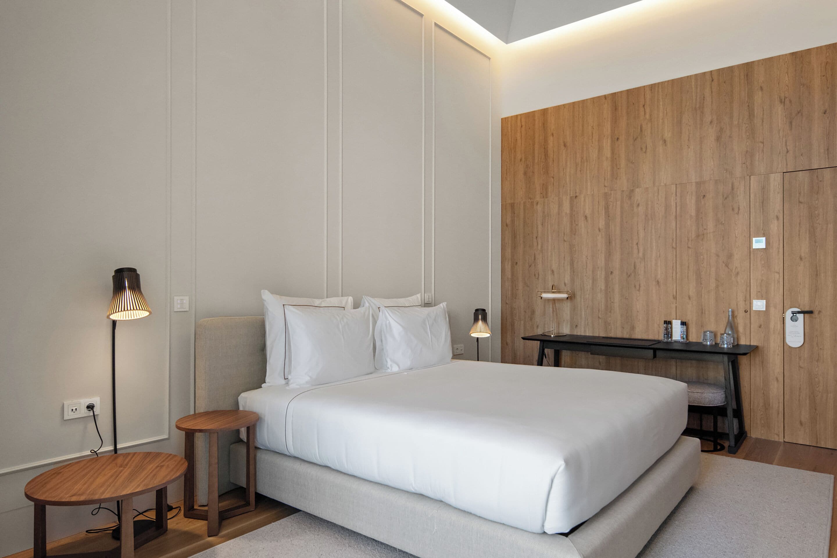 Un dormitorio moderno con una cama grande, dos mesitas de noche, un buró y un armario de madera.