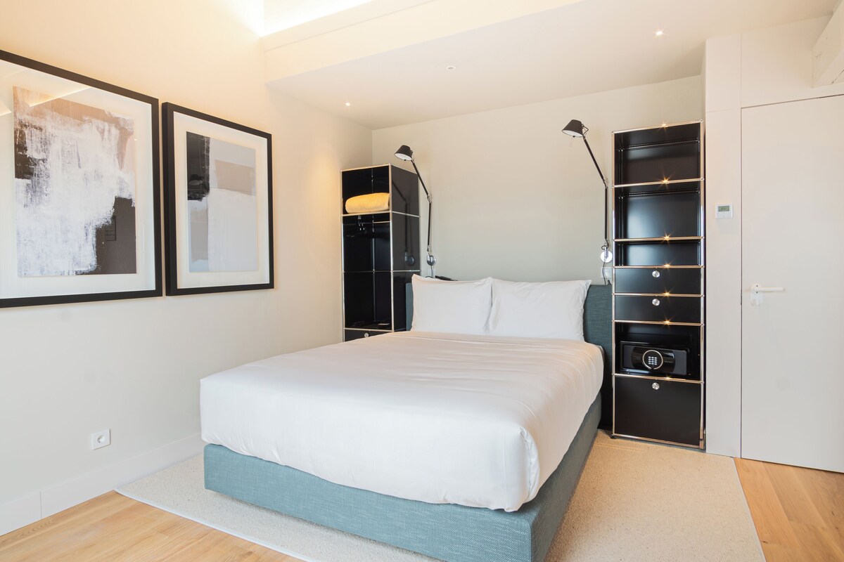 Une chambre à coucher moderne avec un grand lit, une armoire intégrée et deux tableaux abstraits encadrés accrochés au mur.