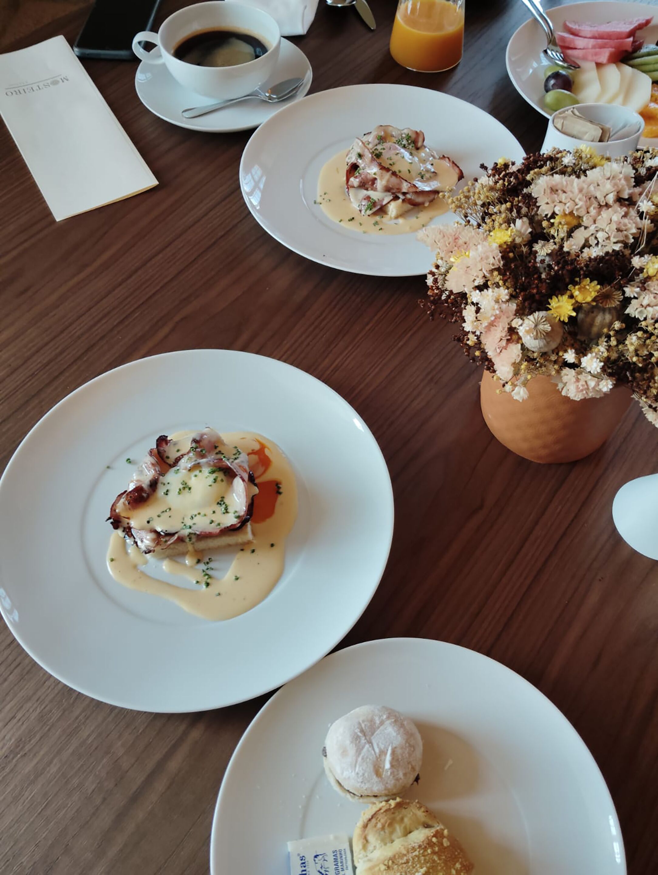 A dining table with plates of food, a coffee cup, a glass of orange juice, and a menu.