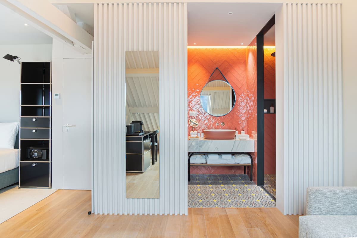 Un baño moderno con tocador, espejo y una pared de acento roja.
