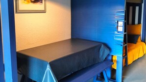 A compact room with a bunk bed, a small table, and a wall-mounted lamp. - Studio Glovettes 35m², Perfect for Ski & Hiking (Villard-de-Lans)