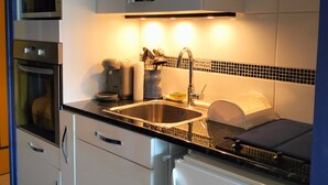 A modern kitchen with stainless steel appliances, a sink, and a microwave. - Studio Glovettes 35m², Perfect for Ski & Hiking (Villard-de-Lans)