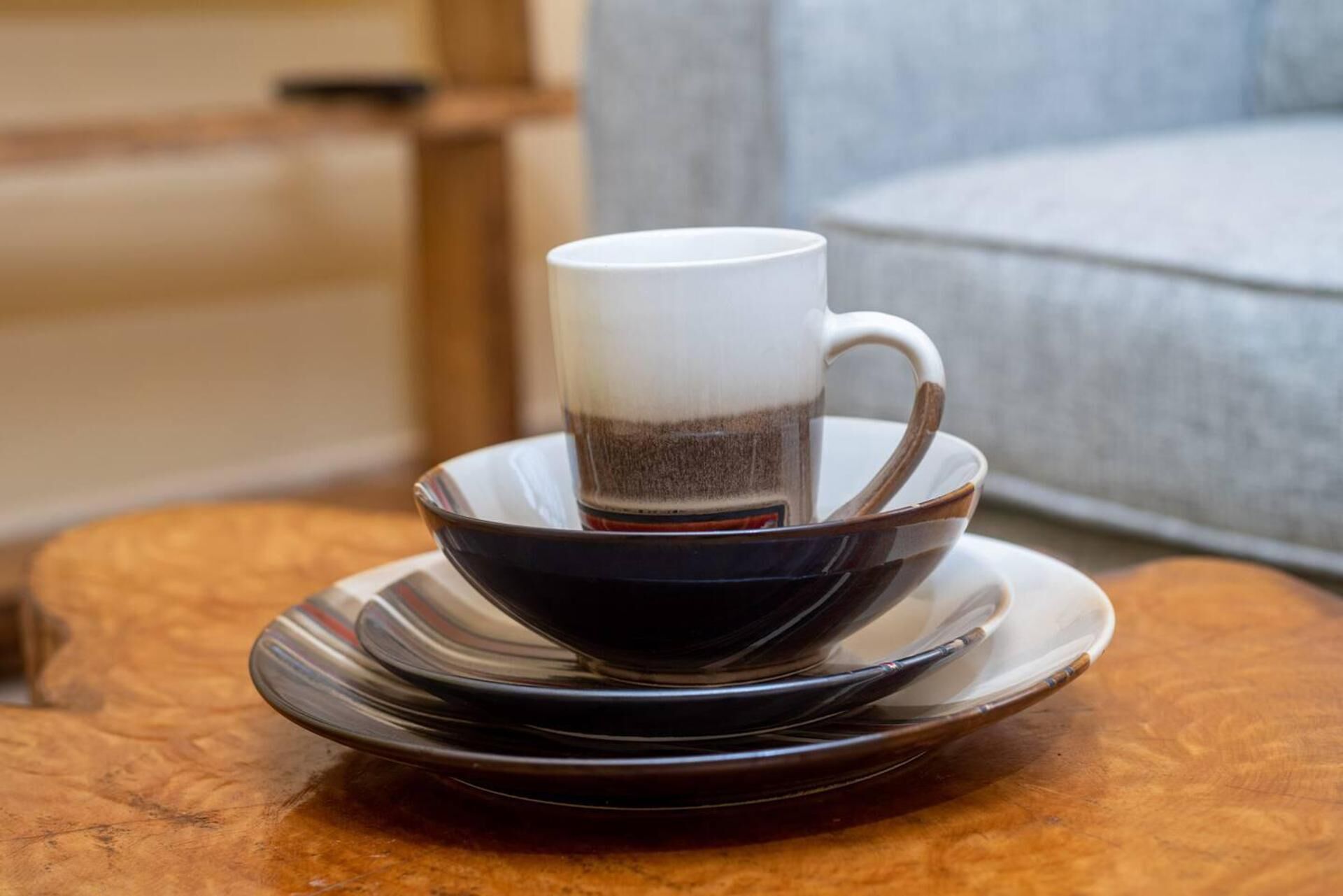Una taza de café sobre un plato y un bol en una mesa redonda.