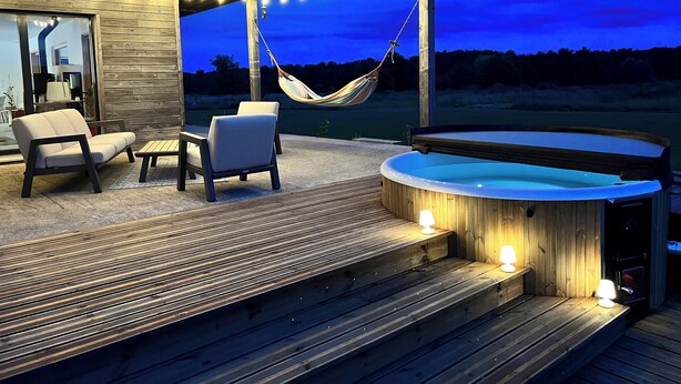Une terrasse extérieure avec un jacuzzi, un coin salon et un hamac.